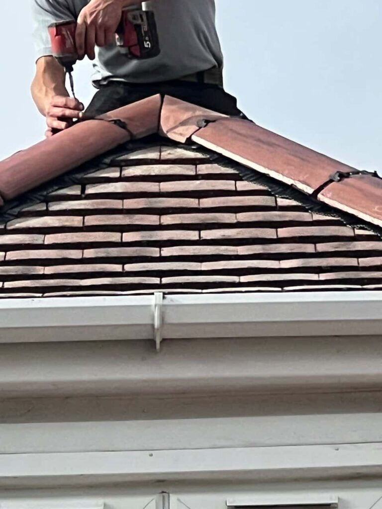 This is a photo of one of the operatives of Clifton Roofing Repairs installing new ridge tiles