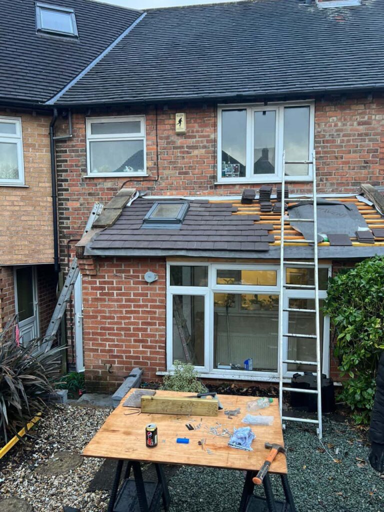 This is a photo of a roof extension that is having new roof tiles installed. This is a photo taken from the roof ridge looking down a tiled pitched roof on to a flat roof. Works carried out by Clifton Roofing Repairs